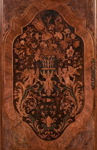 Paire de portes d’armoires aux Renommées en marqueterie de fleurs et incrustation de scagliola, à décor de vases de fleurs, rinceaux et chimères dans des réserves, le vase central à figures de Renommées dans un entourage de rinceaux fleuris.
Par Thomas Hache (1664-1747).
Fin du XVIIe siècle, (accidents).
H : 167 cm, L : 65 cm 

Ces deux portes prennent leur place parmi un groupe d’armoires réalisées par Thomas Hache à Chambery. Si la plupart se caractérisent par la présence d’incrustations de scagliola, elles différent cependant les unes des autres par de petits détails de marqueterie tels que la présence de coqs ou de perroquets. Outre des perroquets, notre armoire peut être distinguée par la présence de chimères de part et d’autre de la réserve supérieure.