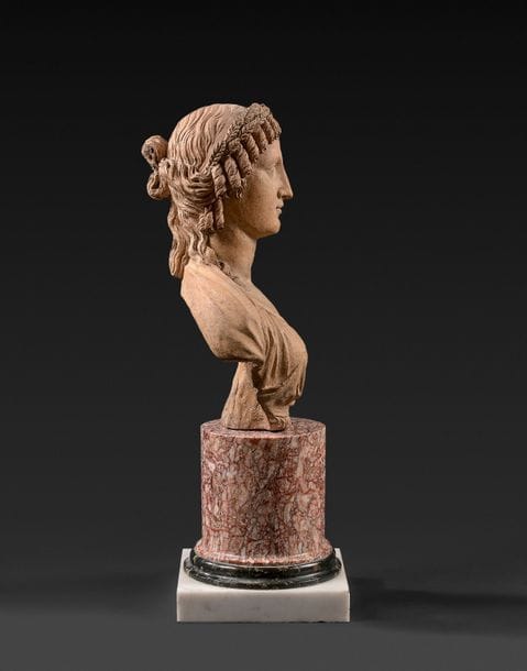 Buste de femme antique en terre-cuite, à tresses et couronne de feuilles de laurier, vêtue d’un drapé, monogrammé AC au revers.
Par Charles-Antoine Callamard (1769-1815).
H (buste) : 30 cm
H (totale) : 47 cm

Disparu à 44 ans, Charles-Antoine Callamard n’a pas eu la production qui lui aurait permis de passer à la postérité, ni même de ne pas injustement tomber dans l’oubli. Elève d’Augustin Pajou, il s’illustra dans le plus pur style néoclassique en vogue à son époque, concourra pour le prix de Rome en 1792 et participa entre 1805 et 1815 aux grandes commandes officielles de l’Empire dont l’arc du Carrousel du Louvre. Comme ultime et tardif hommage, quelques vingt ans après sa mort, David d’Angers, qui réalisa par ailleurs son profil, écrivit ceci à son sujet : « Mon cœur s’émeut au souvenir de cet artiste presqu’oublié maintenant et ce simple nom me fit une impression plus profonde que la pompe des plus vaniteuses épitaphes ».
On doit également à Callamard notamment une Bacchante ainsi qu’une figure allégorique représentant la Liberté terrassant l’hydre du despotisme réalisée à l’âge de 25 ans ; ces deux œuvres toutes les deux réalisées en terre-cuite et conservées aujourd’hui au musée des Beaux-Arts de Rouen.