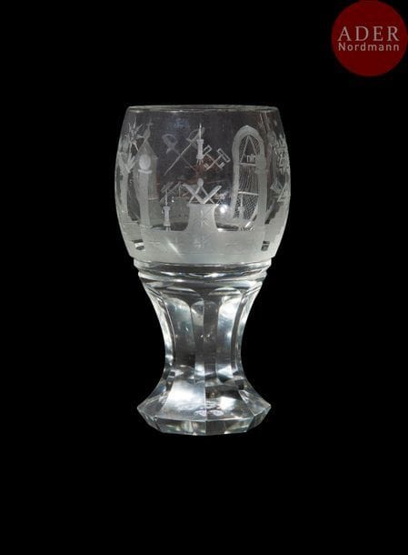 Verre dit « canon » maçonnique en verre taillé, gravé, rond, sur base taillée à huit pans, gravé à décors symboliques, épées croisées, clés croisées, équerre, marteau, truelle, colonnes, perpendiculaire, 5 marches surmontées du triple triangle orné au centre d’une croix. 
Hauteur. : 15 cm
B.E. XXe siècle
