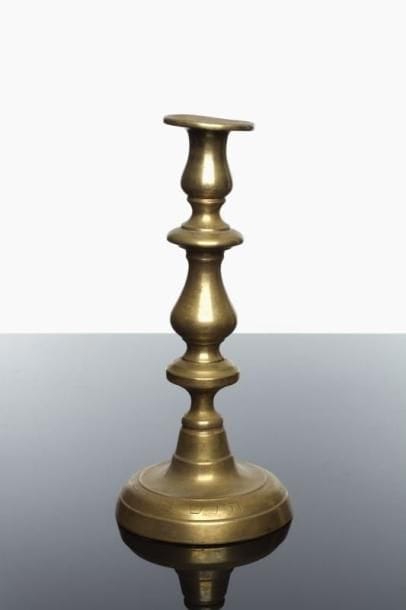 FLAMBEAU DE SHABBAT (seul, d'une paire) - Laiton. Le fût balustre porte sur sa base circulaire une inscription au nom de Hirsch ben Feiss (P) Feffer. Allemagne ou Alsace, XIX ème siècle. Très belle graphie des lettres. Haut.: 29,5 cm.