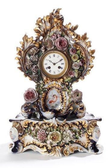 Pendule et son socle, en porcelaine de Paris à décor sur fond gros bleu, en relief, de fleurs et feuillages. Au centre un cartouche rayonnant, présente un Amour tenant une torche. Le cadran signé : «A. BENOIT, Boulevard des Italiens, n°17». Il indique les heures en chiffres romains. Travail attribué à Jacob PETIT. Epoque Napoléon III (très légers éclats et une fente). Hauteur : 50 cm - Largeur : 34 cm Profondeur : 16 cm.