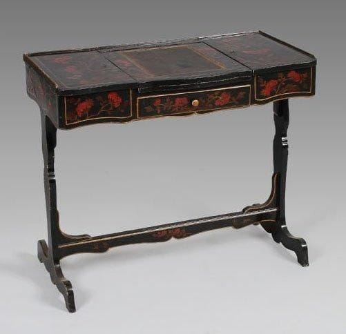 Coiffeuse en laque européen à fond noir à décor rouge et or de branchages fleuris et feuillagés animés d'oiseaux.  Elle présente sur l'entablement, au centre, un abattant garni d'un cuir doré aux petits fers. Ce dernier se soulève, laissant apparaître un miroir articulé. Sur les côtés deux casiers. Un tiroir en ceinture. Montants plats, réunis par une barrette. Pieds en chevalet. Epoque Louis XV. Hauteur : 69,5 cm - Largeur : 81 cm - Profondeur : 42 cm.