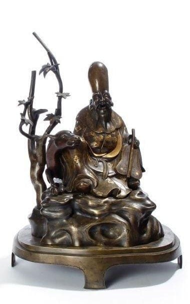 JAPON, XIXe siècle
Groupe en bronze à patine jaune, Fukurukuju assis sur son cerf couché sur un rocher près d'un érable, le vêtement à décor incrusté de fleurs en cuivre rouge.  Hauteur : 46 cm. Manquent les cornes du cerf ; petits accidents. 