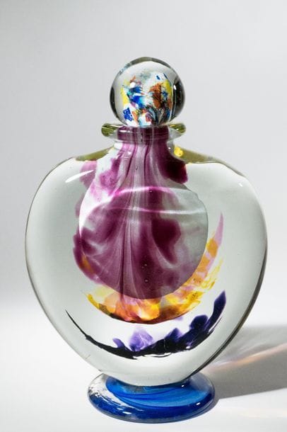 Jean-Claude NOVARO (1943-2015)
 Flacon épaulé sur piédouche de forme aplatie en verre soufflé transparent, inclusion d’émaux jaune et mauve en son centre et multicolores sur le bouchon.


Signé et daté 2007 sous la base.


Hauteur : 38 cm