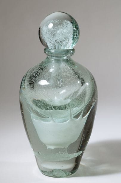 Jean-Claude NOVARO (1943-2015)
Flacon ovoïde en verre soufflé, inclusion d’émail blanc luminiscent finement bullé en partie haute et sur le bouchon, de manière plus dense en forme d’étoile en partie basse.


Signé et daté 2003 sous la base.


Hauteur : 28 cm.