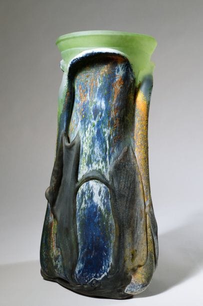 Jean-Claude NOVARO (1943-2015){CR}Vase en verre soufflé de forme étirée à décor irisé d’émaux multicolores, col vert, cordons bleutés appliqués sur une surface non doublée.{CR}
Signé et daté 2003 sous la base.{CR}
Hauteur : 38 cm.