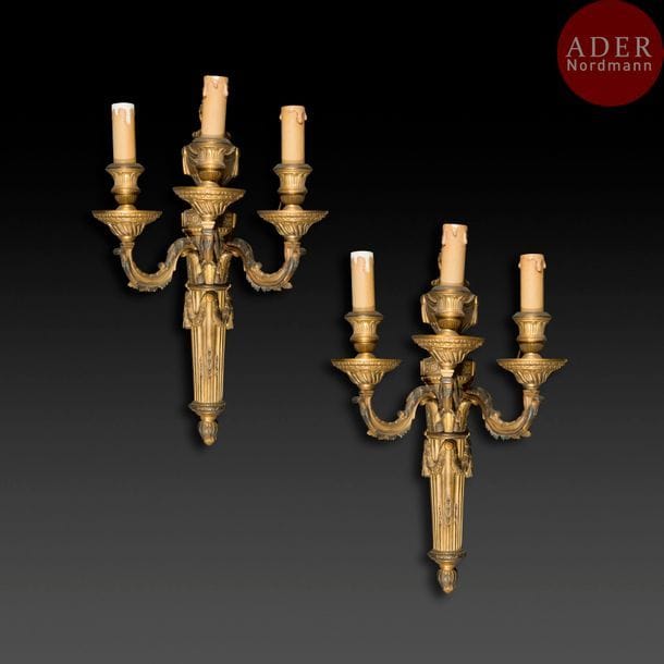 Quatre appliques en bronze doré à trois lumières, le fût à cannelures et guirlandes surmonté d’un vase enflammé à draperies.
XIXe siècle (usures)
H : 47 cm