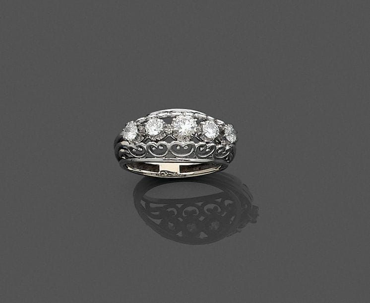 Bague en fils d’or gris 18K (750), ornée de 5 diamants ronds de poids croissant, la corbeille ajourée de cœurs. Travail français des années 1950. Tour de doigt : 57. 
Poids brut : 5,3 g