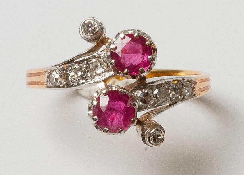 Bague croisée en or 18K (750), sertie de deux rubis, l’épaulement agrémenté de diamants ronds. 
Tour de doigt : 54. 
Poids brut : 3,3 g