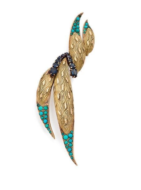 Broche-clip flammes stylisées en or 18K (750), agrémentées de turquoises cabochons et de saphirs ronds. Travail français des années 1960. hauteur : 9 cm environ. 
Poids brut : 18,8 g