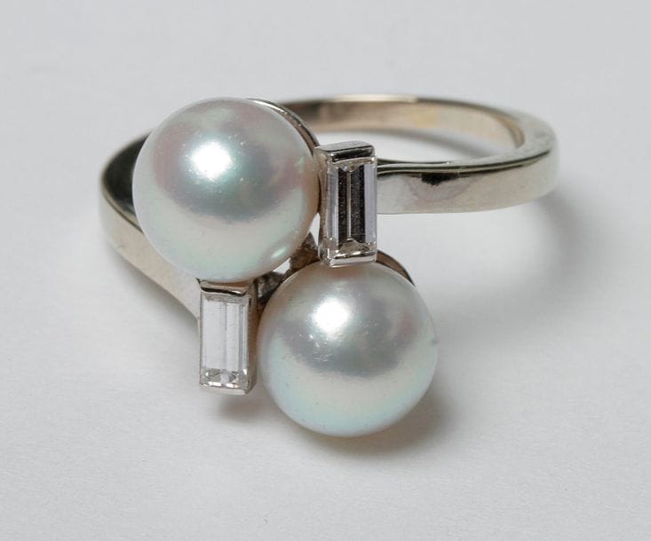 Bague en or gris 18K (750) et platine Toi & Moi, ornée de 2 perles de culture et 2 diamants calibrés. 
Poids brut : 4,8 g