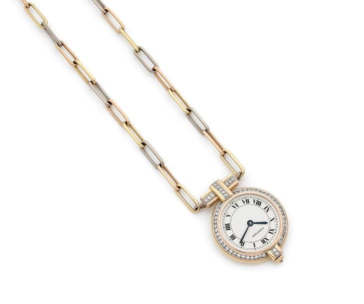 CARTIER vers 1980
N°960730036
Montre pendentif pour femme en trois ors 18K (750) modèle Vendôme. Lunette sertie de diamants, cadran blanc index chiffres romains formant les heures, mouvement à remontage mécanique signé Cartier No 13490. Chaîne à mailles gourmette en trois ors 18K (750).
Cadran, boîtier et mouvement signés. 
Poids brut : 41,7 g 