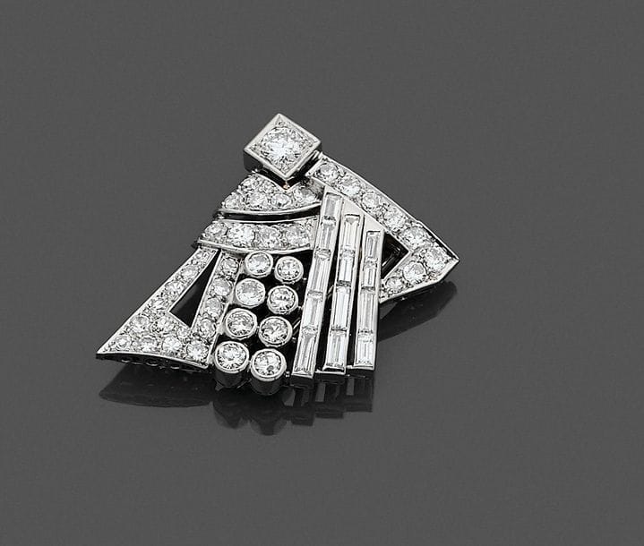 Clip en platine dessinant un motif géométrique, ajouré, serti de diamants ronds et de trois lignes de diamants calibrés. Travail des années 1925. Hauteur : 3,5 cm environ. 
Poids brut : 16,2 g (système en or 18K)
