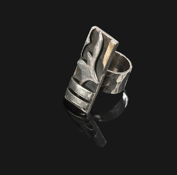 Jean DESPRÉS (1889-1980)
Bague moderniste en argent et or.
La platine rectangulaire aux motifs en applications de deux barrettes et d’une forme libre sur fond martelé patiné anthracite.
Le large anneau également traité en martelage.
Signée J. DESPRÉS à la pointe à l’intérieur de l’anneau et porte les poinçons de Maître Orfèvre et de garantie sur l’anneau.
Poids : 21,6 g 
Provenance :
- M. et Mme X., Avallon. Œuvre acquise directement auprès de Jean Després.
- Mme D., Sarzeau (Bretagne). Fille des précédents.