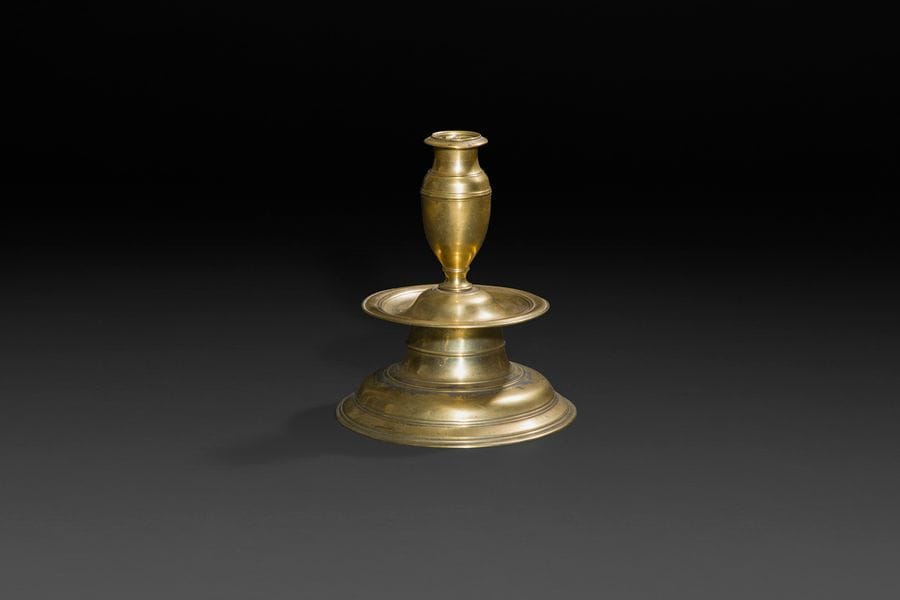 Chandelier en laiton. Fût tourné en balustre, large coupelle et base circulaire moulurée. 
XVIIe siècle
H?: 18,6?cm, D?: 15,7cm
(petit manque à la bobèche) 