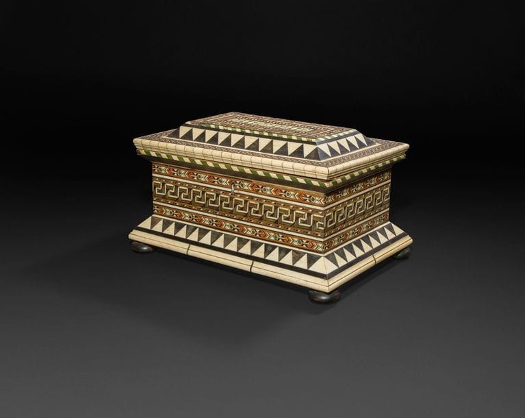 Grand coffret en marqueterie d’ébène, bois teinté, os, ivoire et ivoire teinté, à décor géométrique de triangles, losanges et frises de grecques?; reposant sur des pieds circulaires (refaits)?; probablement avec une prise au couvercle à l’origine.
Attribué à l’atelier des Embriacchi, Venise, XVe siècle.
H?: 23?cm, L?: 38?cm, P?: 25?cm
RESTAURATIONS, NOTAMMENT AUX FRISES DE TRIANGLES 

Plusieurs coffrets de taille plus modeste (autour de 30 cm de large) viennent illustrer l’usage du décor géométrique dans l’atelier des Embriacchi, citons à cet égard les exemplaires passés récemment en vente publique : Sotheby’s Londres, le 2 juillet 2013, lot 54, Sotheby’s New York, le 30 janvier 2014, lot 339 et Sotheby’s Paris, le 28 novembre 2016, lot 27.