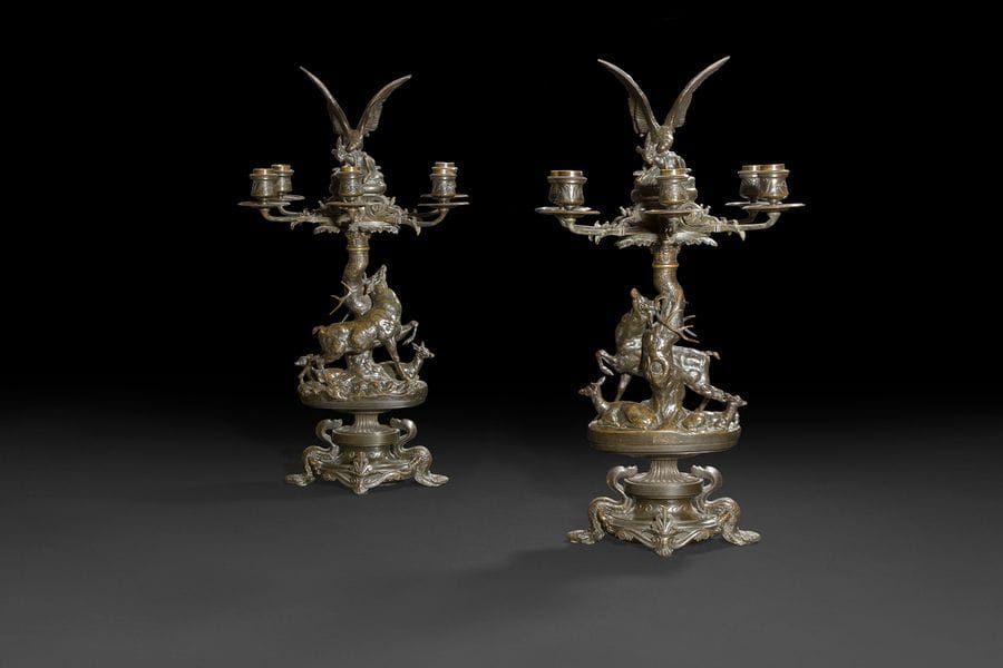 Paire de candélabres aux cerfs en bronze à patine brun foncé, à six bras de lumière entourant un aigle attaquant un lièvre, reposant sur un fût simulant un arbre tors, le cerf accompagné d’une biche et d’un faon, la base à double piédouche orné de batraciens, palmettes et frise de postes?; signé Barye (sur le tertre).
Par Antoine-Louis Barye (1795-1875).
Vers 1870.
H?: 58?cm, L?: 57?cm
ACCIDENTS

Bibliographie?:
I. Leroy-Jay Lemaistre, «?La griffe et la dent?», cat. exp., musée du Louvre, Paris, 1996, p. 63.
M. Poletti et A. Richarme, «?Barye?», Paris, 2?000, p. 376.
O. Gabet, «?Un marchand entre deux Empires, Elie Fabius et le monde de l’art?», Paris, 2011, p. 55.

Provenance?:
Ancienne galerie Fabius frères, vente Paris, Sotheby’s, les 26 et 27 octobre 2011, lot 275.

MM. Poletti et Richarme situent ces ambitieux candélabres à la fin de la carrière de Barye, vers 1870, mettant en valeur la synthèse à laquelle parvient le sculpteur entre l’art animalier et l’inspiration néoclassique. On sait qu’Antoine-Louis Barye réalisa également ces deux groupes de façon séparée et indépendante?: «?Milan emportant un lièvre?» et «?Cerf dépouillant ses bois, daine et faon?». Il s’agit de l’une des rares fontes anciennes de ce modèle, réalisée du vivant de l’artiste.