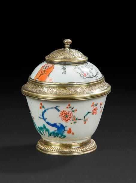 JAPON ET CHINE
Petit bol en porcelaine du Japon à décor polychrome Kakiemon de branches de prunus fleuris et un couvercle en porcelaine de Chine à décor de poèmes et figures chinoises. Monture en vermeil avec poinçon probablement coquille couronnée, Paris 1732-1738.
XVIIIe siècle. 
H : 8,5 cm, D : 6,8 cm, poids brut : 107,6 g
Un éclat et fêlure au couvercle.