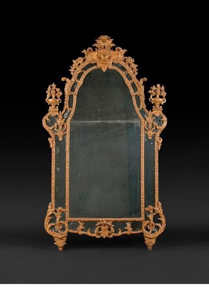 Miroir en bois doré à décor ajouré de rinceaux et guirlandes de fleurs, les montants surmontés de vases et le fronton à mascaron.
Époque Louis XV (accidents).
H : 191 cm, L : 110 cm