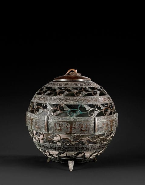 JAPON - époque MEIJI (1868-1912)
Lanterne de forme sphérique en bronze à patine brune à décor ajouré de branches de ginko et frises de masques de taotie stylisées alternées.
H : 49 cm