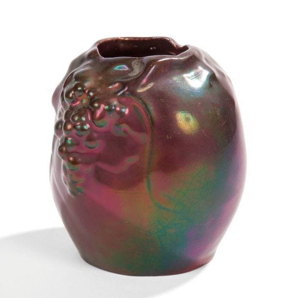 FAÏENCERIE DE MONTIÈRES
Raisins 
Petit vase ovoïde à ouverture mouvementée. Épreuve au décor en relief et émaillée aubergine aux effets d’irisations. Petits éclats sous la base. Marqué MONTIÈRES vers la base. H. 9,5 cm 