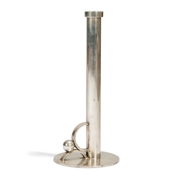 JEAN DESPRÉS (1889-1980)
Rare et exceptionnel bougeoir à main moderniste. Épreuve en métal argenté à la surface traitée entièrement lisse. Le fût cylindrique sommé d’un large ressaut repose de façon excentrée sur une base circulaire. La prise constituée d’un demi et d’une fraction de cercle est agrémentée d’une large sphère. Frappé du poinçon de Maître Orfèvre sur la base. H. 20,5 cm

Provenance :
- Ancienne Collection Mme C. à Avallon. Œuvre acquise par cette dernière directement auprès de l’artiste.
- Acquis pas l’actuel propriétaire auprès de la précédente.