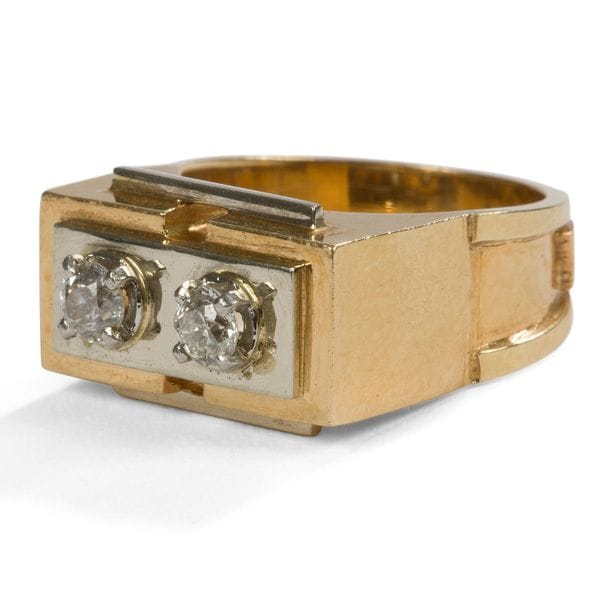 JEAN DESPRÉS (1889-1980)
Bague moderniste en or jaune, or blanc et diamants. La plateforme rectangulaire en or jaune présente une platine centrale en ressaut réalisée en or blanc et accueillant deux diamants. Deux barrettes latérales en or blanc, simulant des agrafes, viennent achever le décor de la platine. L’anneau est enrichi de deux ressauts latéraux. Signée J. DESPRÉS à la pointe à l’intérieur de l’anneau et porte le poinçon de garantie à l’extérieur de l’anneau. Poids brut : 9,5 g