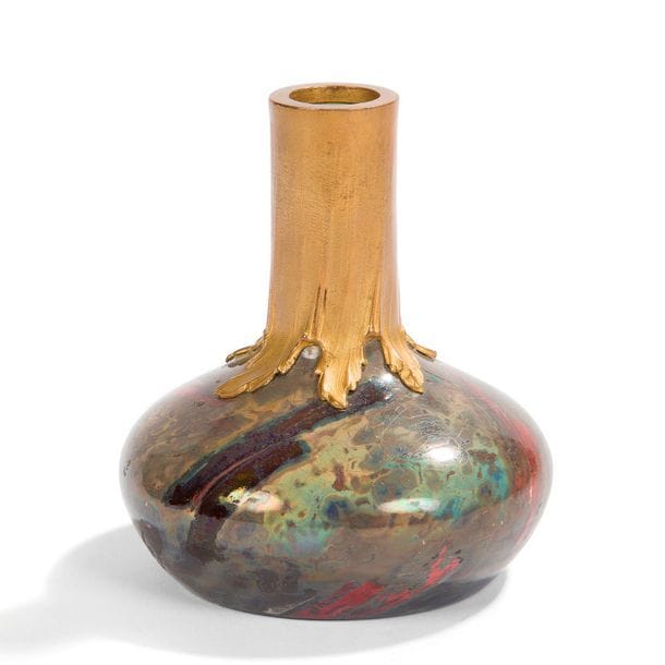 KELLER & GUÉRIN À LUNÉVILLE 
Vase à panse aplatie et à col droit. Épreuve en céramique émaillée irisée polychrome façon marbre ; le col agrémenté d’une monture en métal doré à effet de coulures. Griffures éparses sur la couverte et un petit éclat sous la base. Marqué LUNÉVILLE et la lettre T sous la base. H. 10 cm 