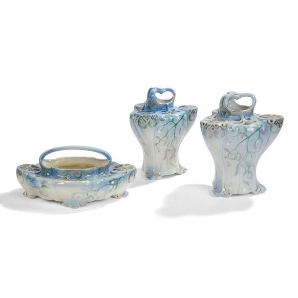 EDMOND LACHENAL (1955-1948) & KELLER & GUÉRIN A LUNÉVILLE POUR LES ANNALES POLITIQUES ET LITTÉRAIRES
Gui, modèle créé en [1900]
Garniture comprenant une jardinière et deux vases. Épreuves en faïence ajourée, le décor végétal émaillé vert, violet et à l’or sur fond dégradé du bleu au blanc. Chaque pièce porte le tampon Les Annales Polit. et Lit., K.G., E. LACHENAL sous la base. 
H. vases : 27 cm – L. jardinière : 31 cm 
À noter : 
Une partie de service de ce modèle est conservé dans les collections du musée d’Orsay. 