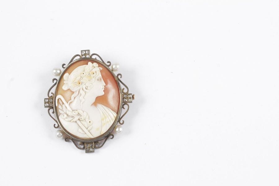 Camée coquille sculpté d'une jeune femme de profil "à l'Antique", la monture en métal agrémentée de diamants taillés en roses et de perles. Hauteur: 5,5 cm environ. 