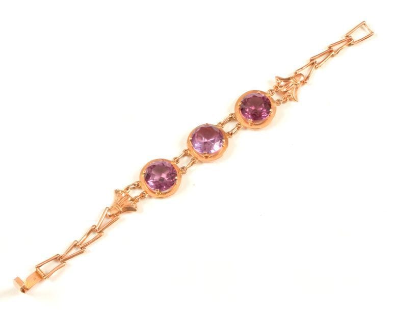 Bracelet en or 14K (585 ‰), articulé de trois motifs sertis chacun d'une pierre violette, agrémenté de fleurs de lotus ciselées. 

Poids brut : 16,1 g
