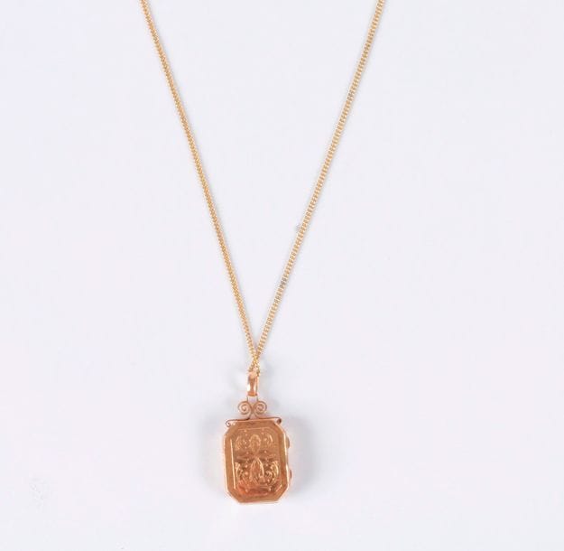 Pendentif porte-souvenir en or 18K (750), il recèle un compartiment. Poids brut: 10,2 g (enfoncements, on joint une chaîne en métal)