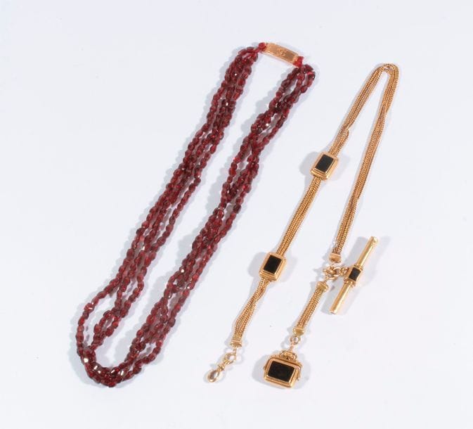 Lot de bijoux comprenant une giletière en or 18K (750) et onyx.

Poids brut : 28,8 g

On joint un collier de perles de grenats, fermoir or 18K (750)

Poids brut : 27,1 g