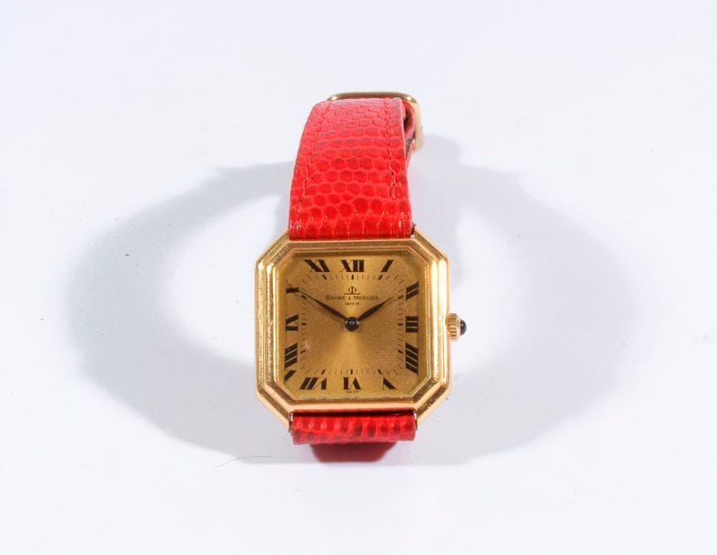 BEAUME & MERCIER. Montre bracelet de dame carrée en or. Fond doré, chiffres romains. Mouvement mécanique.

Bracelet en cuir rouge.

Poids brut : 24,3 g