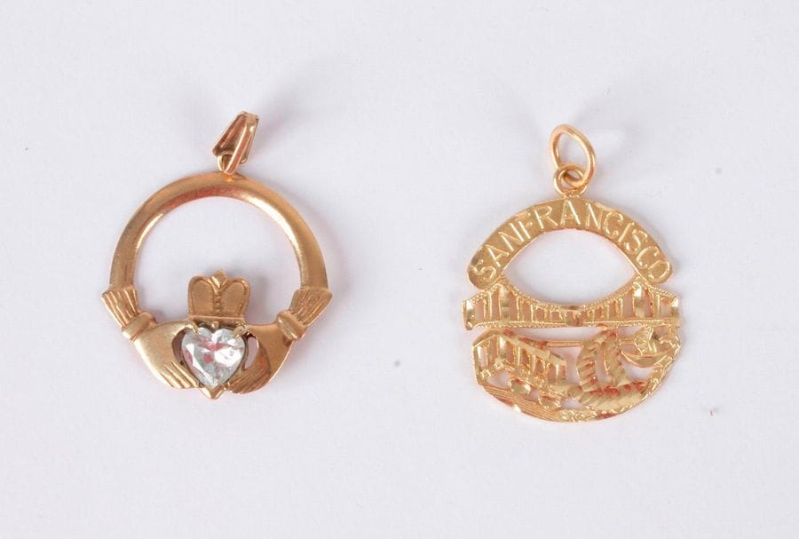 Lot de 2 pendentifs, l'un en or 14K (585) orné du pont de San Francisco, l'autre en or 9K (375) orné d'un cœur couronné. Poids bruts respectifs: 2,1 et 1,9 g