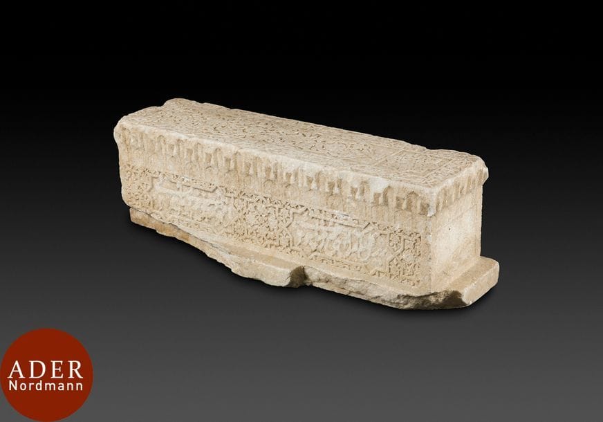 Cénotaphe en marbre blanc, Asie centrale, fin XVe – XVIe siècle
Cénotaphe rectangulaire sculpté sur le dessus d’une arcature polylobée garnie d’un décor couvrant de rinceaux végétaux, palmettes bifides et fleurs de lotus, et surmontée d’un cartouche inscrivant une étoile à huit pointes garnie du même décor. Large frise de bordure d’une succession de cartouches à inscriptions illisibles. Faces latérales sculptées d’une frise alternant étoiles à huit pointes et cartouches à extrémités étoilées inscrits de vers persans en calligraphie nasta’liq sur les grands côtés, petits côtés lisses et sans décor. Une corniche de muqarnas court sur tout le pourtour de la stèle qui repose sur une base plate fragmentaire. 
Dim. : 80 x 24 x 25 cm 
état : usures, effacement du décor, manques. 
Provenance : collection française depuis 1980. 
La corniche de muqarnas évoque l’architecture timouride, par exemple, le mausolée de Gur-i Mir à Samarcande. 

A white marble funerary stele, Central Asia, late 15th - 16th century