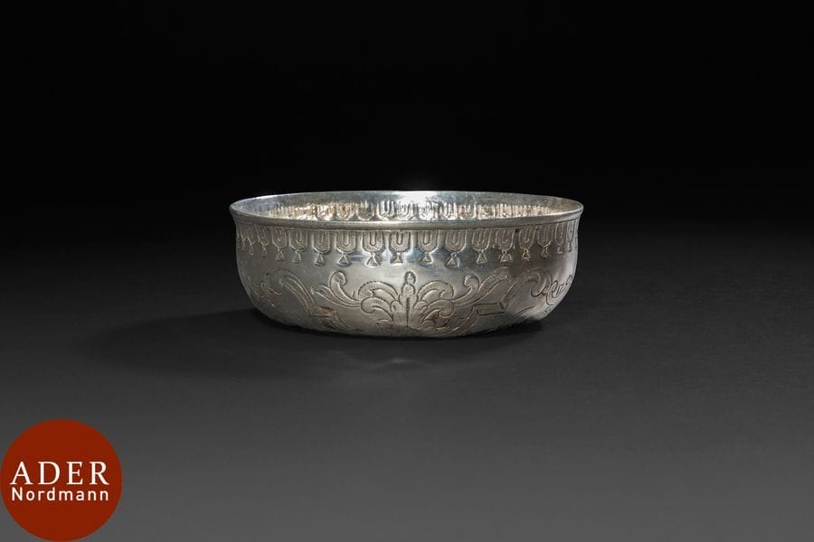 Bol de hammam taza en argent, Turquie ottomane, XIXe siècle
Bol cylindrique à parois droites et bosse centrale. En argent poinçonné d’une tughra illisible. Décor rocaille repoussé sur la bosse, gravé sur les parois et d’une frise de festons sous la lèvre. 
Diam. : 12 cm ; H. : 4 cm ; PB : 99 g 
État : quelques bosses et rayures.

An Ottoman silver hammam bowl taza, Turkey, 19th century