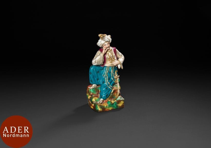 Paris, Homme au turban assis sur un rocher, en porcelaine dans le goût de Jacob Petit, XIXe siecle
Flacon photophore en porcelaine émaillée polychrome et dorée représentant un homme enturbanné vêtu d’un sarouel, de babouches et d’un petit gilet portant des armes à la ceinture. Pièce constituée de trois parties : un corps en deux éléments s’emboîtant au niveau de la taille du personnage et un bouchon couronnant le sommet du turban.
H. : 28 cm
État : léger éclat d’émail sur un doigt.

A Jacob Petit style porcelain depicting a man in a turban sitting on a rock, Paris, 19th century