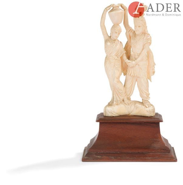 INDE - Vers 1900
Groupe en ivoire, couple debout, la femme portant une jarre sur la tête.
H. : 15,5 cm - Poids : 300 g ; sur socle en bois.