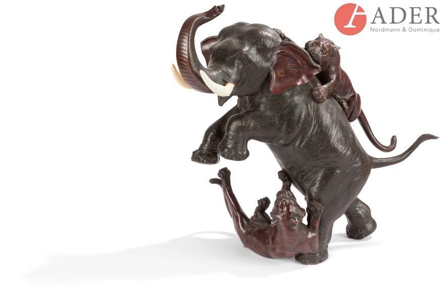 JAPON - Époque MEIJI (1868 - 1912)
Groupe en bronze à patine brune, éléphant se dressant sur ses pattes arrières, assailli par deux tigres. Les défenses en ivoire. Signé Mitsumoto. 
H. : 50 cm
(L’une des défenses restaurée et remplacée de résine).