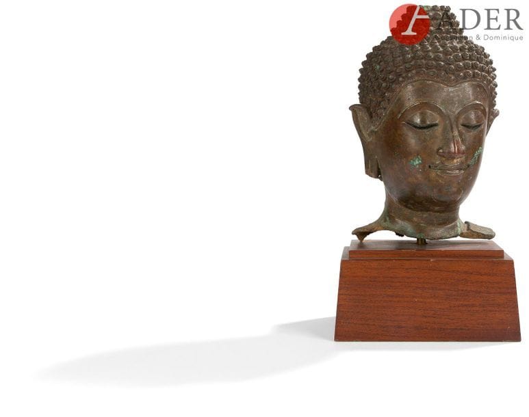 THAÏLANDE - XVIIe siècle
Tête de bouddha en bronze à patine brune, les yeux entrouverts, esquissant un léger sourire, les cheveux frisés en chignon.
H. : 24 cm
(Manque une partie de l’ushnisha et des lobes d’oreilles). Socle en bois.