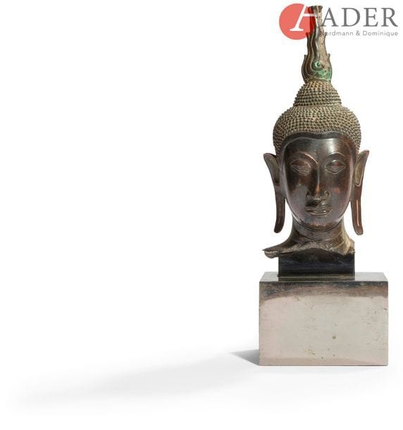THAÏLANDE - XVIIe siècle
Tête de bouddha en bronze à patine brune, les yeux entrouverts, esquissant un léger sourire, l’ushnisha dans le prolongement du chignon.
H. : 28,8 cm
