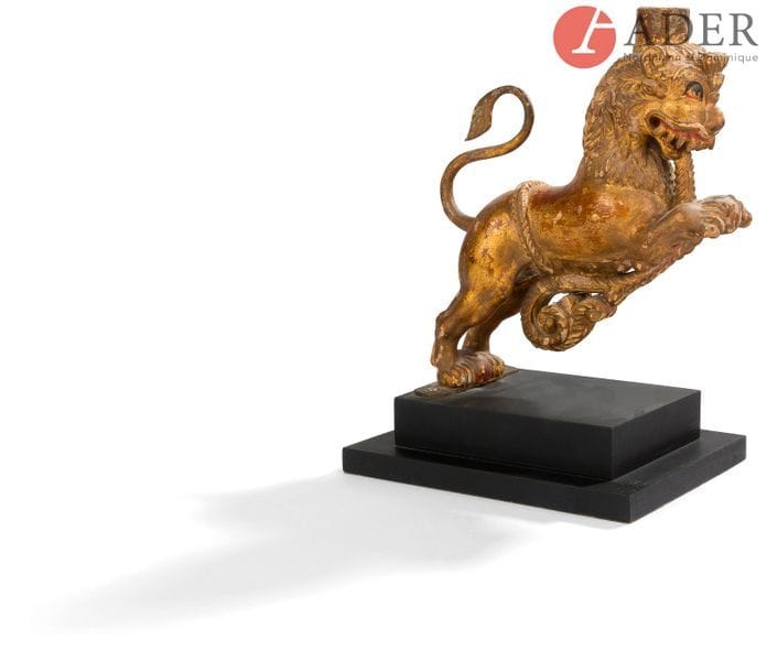 BIRMANIE - XVIIIe siècle
Lion en bois sculpté laqué or, dressé sur ses pattes arrières, une corde dans la gueule se terminant en rinceau sous son ventre. 
(Petits manques et restaurations).
H. : 25 cm