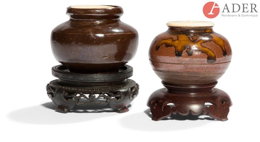 JAPON - Époque MEIJI (1868 - 1912)
Deux chaïre, l’un de forme ronde en grès émaillé brun et coulures fauves, l’autre de forme balustre aplatie en grès brun émaillé chocolat. (Égrenures au bord).
H. : 5,5 et 6,2 cm ; bouchons en ivoire, socles en bois.
