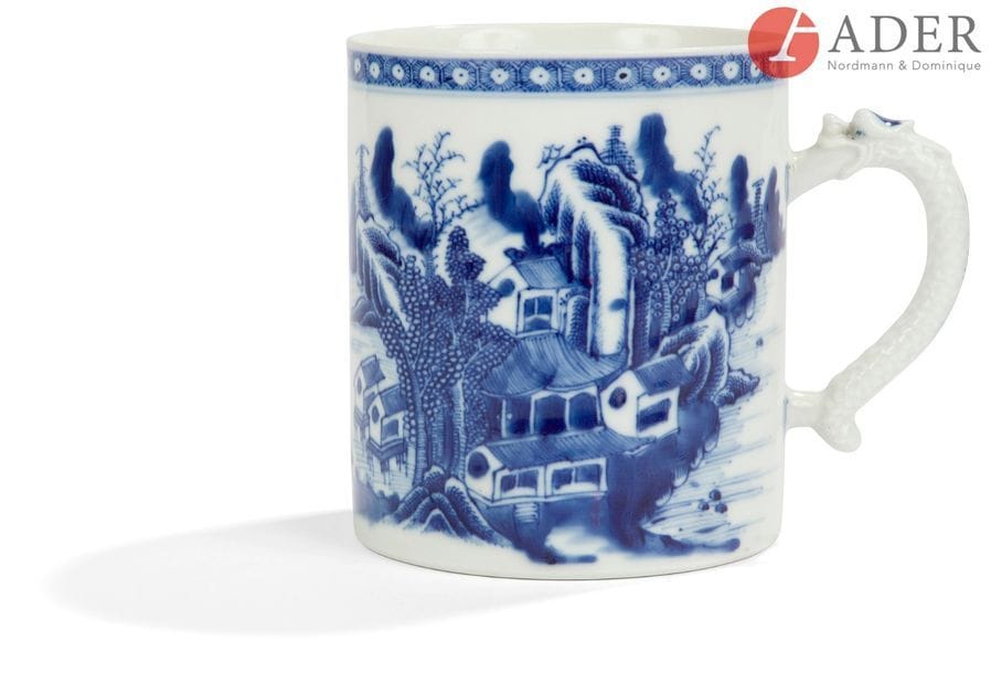 CHINE - Époque QIANLONG (1736 - 1795)
Tasse en porcelaine bleu blanc à décor de paysage lacustre jonché de cabanons, l’anse formant dragon. (Anse recollée).
H. : 13,1 cm