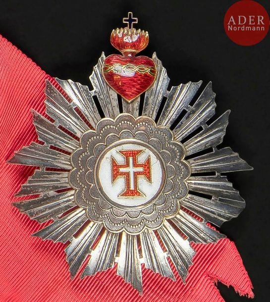 PORTUGAL
ORDRE DU CHRIST, créé en 1319.
Ensemble de grand-croix, modèle de la Royauté comprenant :
- bijou de grand-croix à encadrement en vermeil, centre en émail, à la croix du christ, surmonté d’un motif en argent émaillé au Sacré cœur, biface. Avec un fragment d’écharpe et son nœud.
85?x?55?mm - Poids brut : 100?g
- plaque. En argent et vermeil. Croix du Christ et Sacré cœur en or émaillé. Revers à attache basculante double et marque du fabriquant J.A. DA COSTA à Lisbonne.
70?mm - Poids brut : 40?g
T.T.B.