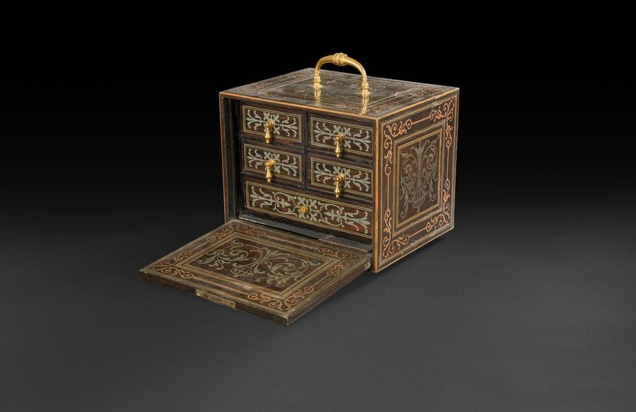 Petit cabinet en marqueterie de cuivre et étain sur fond d’ébène (toutes faces), à décor de rinceaux et encadrements, ouvrant à un abattant découvrant cinq tiroirs ; une poignée au-dessus.
Style Régence, XIXe siècle.
H : 16,5 cm, L : 20 cm, P : 16 cm
