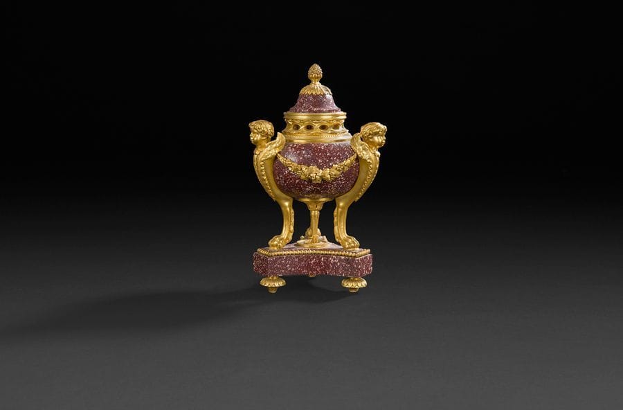 Vase pot-pourri formant flambeau en porphyre à monture de bronze doré, les montants à bustes d’enfant ailé reposant sur des pieds en griffe et une base triangulaire.
Style Louis XVI, XIXe siècle.
H : 18 cm