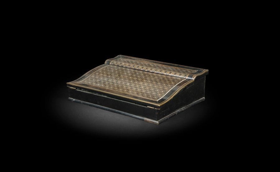 Écritoire en marqueterie de laiton sur fond de bois noirci, à décor de rosette, ouvrant à un abattant et un compartiment à écrire.
Signe de la maison Tahan à Paris
Époque Napoléon III (accidents et manques)
H : 6 cm, L : 33 cm, P : 25 cm