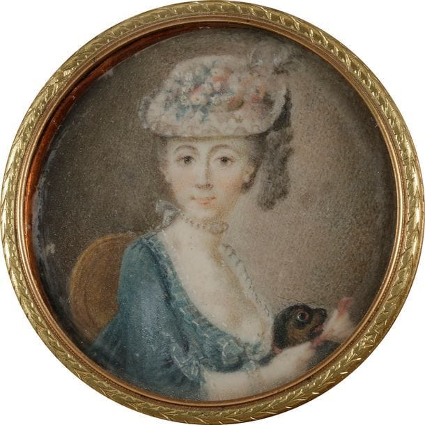 École française du XVIIIe siècle
Jeune Femme assise avec son chien carlin, les deux mains visibles tenant un éventail, en robe bleue et chapeau paré de fleurs et fruits.
Miniature sur ivoire vers 1780, diam à vue 4,5 cm, cerclée d’or de deux couleurs, diam. 5,3 cm, dans un cadre à miniature en bois noirci à visière de laiton doré, rect. H. 11,4 x 11 cm.
(petit frottement à gauche)
On y joint :
- un portrait d’homme en buste vers la droite, en costume vert et perruque, miniature à l’huile du XVIIIe siècle probablement sur cuivre, diam. à vue 4 cm (manques en périphérie, vernis jauni), dans un cadre en bois doré surmonté d’un noeud, H. totale 8 cm